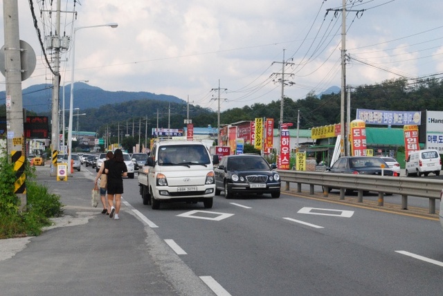 ▲ 지난 5일 오후 3시께 남양주시 일패동 경춘국도에서 시민 2명이 빠른 속도로 지나는 차량 사이로 아슬아슬하게 통행하고 있다. 하지은기자 (1)