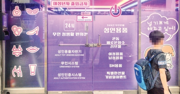 21일 오후 인천 미추홀구 한 초등학교 인근 무인 성인용품 판매점 앞을 초등학생 지나고 있다. 조주현기자